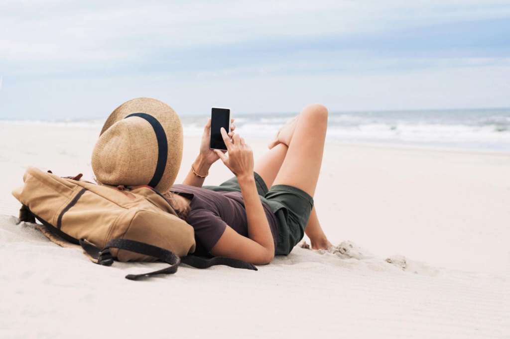 woman using her phone on a beach vacation